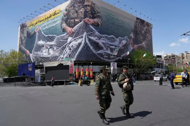 FILE - Two police officers walk in front of an anti-US billboard in Tehran, Iran, Sunday, April 5, 2026. (AP Photo/Vahid Salemi, File)