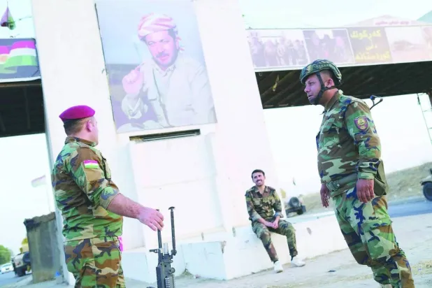 Peshmerga fighters are positioned beneath a portrait of Masoud Barzani in Kirkuk (file photo – EPA)