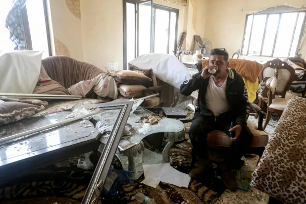 مواطن يشرب الشاي في بيته المتضرر في بلدة قانا في جنوب لبنان (أ.ف.ب)