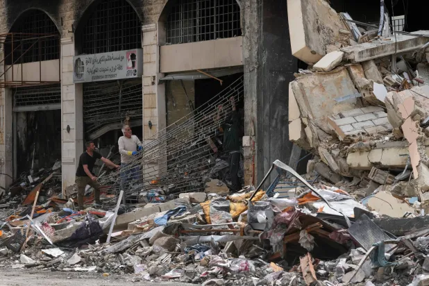 مواطنون لبنانيون يزيلون الأنقاض من محل تجاري دُمِّر نتيجة القصف الإسرائيلي في مدينة النبطية بجنوب لبنان (أ.ب)