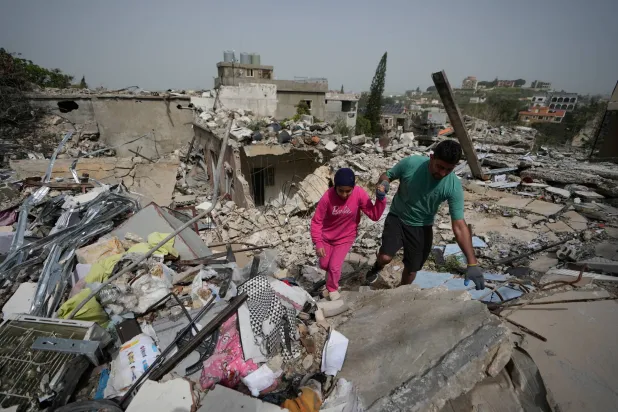 Residents walk on the rubble of destroyed houses on the second day of a ceasefire between Hezbollah and Israel in Jibchit village, south Lebanon, Saturday, April 18, 2026.(AP Photo/Mohammed Zaatari)
