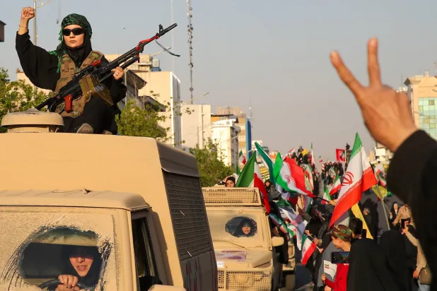 إيرانية تحمل سلاحاً خلال مسيرة في طهران الجمعة (د.ب.أ)