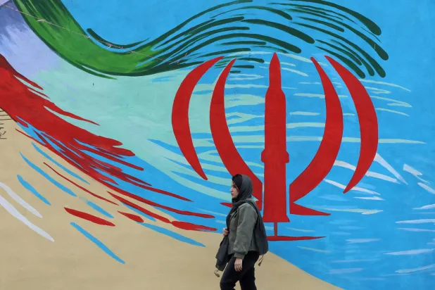 An Iranian woman walks next to a wall painting of Iran’s national flag on a street in Tehran, Iran, 20 April 2026. (EPA)