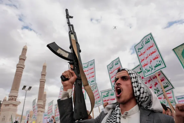 عنصر حوثي يرفع بندقية خلال حشد في صنعاء للتضامن مع إيران و«حزب الله» اللبناني (رويترز)
