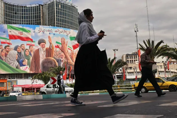 Commuters make their way past a giant billboard of slain Iranian supreme leader Ali Khamenei at the Valiasr Square in Tehran on April 19, 2026. (AFP)