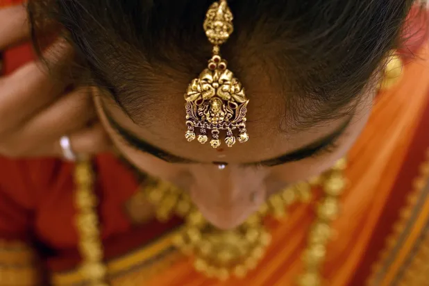 هندية ترتدي قطعة من الحُلي الذهبية داخل متجر مجوهرات في بنغالور (إ.ب.أ)