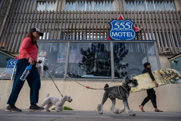 سيدة تسير مع كلابها أمام فندق في مدينة فوجيساوا اليابانية (أ.ف.ب)