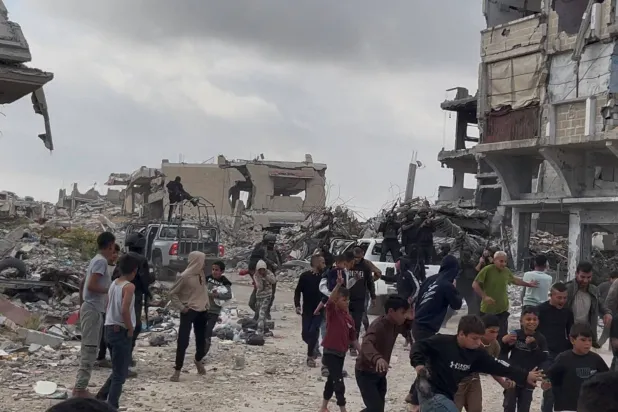 فلسطينيون إلى جانب مقاتلين من فصائل غزة عقب اشتباكات مع ميليشيات مدعومة من إسرائيل في خان يونس جنوب القطاع (صورة من فيديو بثته رويترز)