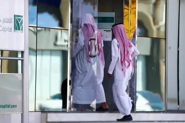 أفراد يدخلون أحد فروع «البنك الأهلي» في السعودية (رويترز)