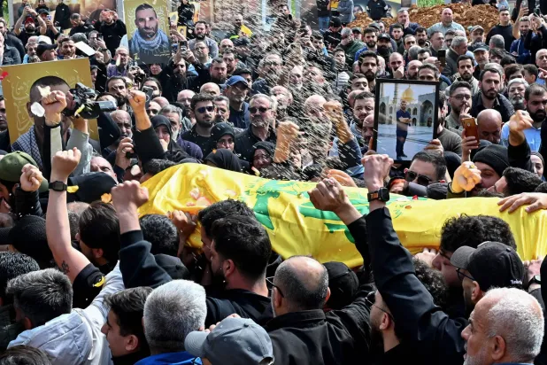 Mourners carry the flag-draped casket of a member of the Iran-backed Hezbollah group who was killed in southern Lebanon during their funeral in the Kafaat area in Beirut's southern suburbs on April 20, 2026. (AFP)