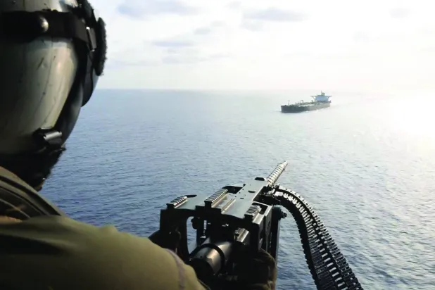 لقطة من فيديو لجندي أميركي على متن مروحية وهو يوجه تحذيراً إلى سفينة إيرانية قرب مضيق هرمز أمس (سنتكوم)