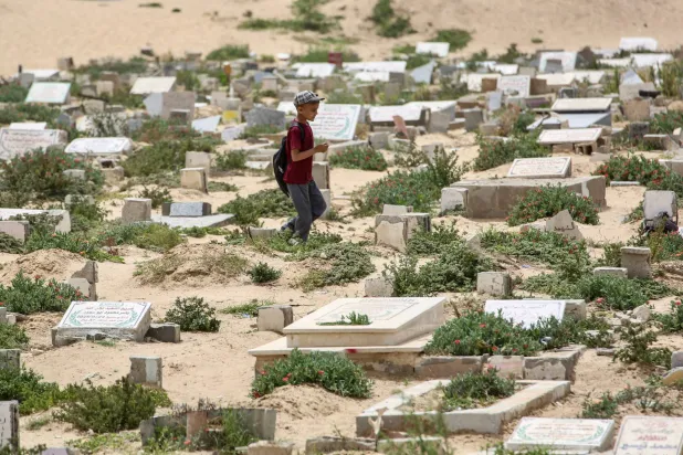 طفل يسير في مقبرة خان يونس جنوب قطاع غزة (أ.ف.ب)