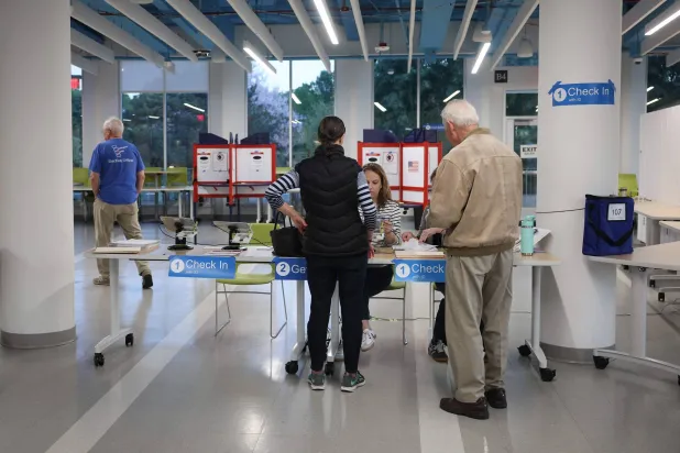 ناخبون يسجلون أسماءهم لدى موظفي الاقتراع قبل الإدلاء بأصواتهم في مركز اقتراع في أرلينغتون - فيرجينيا (أ.ف.ب)