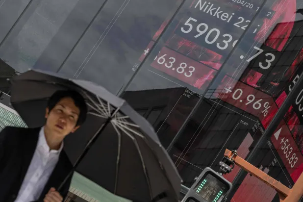 رجل يمر أمام شاشة تعرض حركة الأسهم بالعاصمة اليابانية طوكيو (أ.ف.ب)