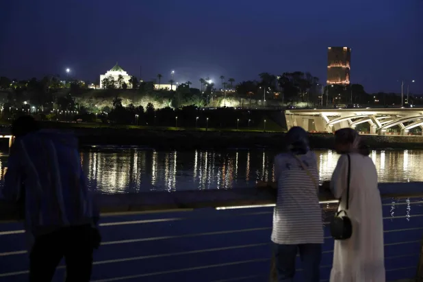  People stand looking across the river at the skyline in the coastal city of Rabat on April 20, 2026. (AFP) 