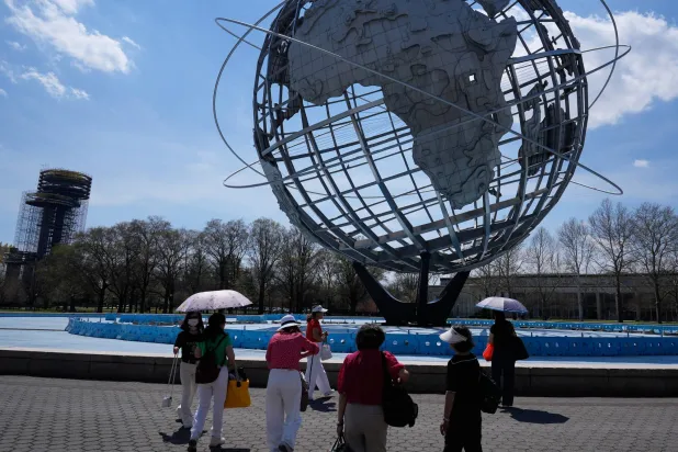 أشخاص يحملون مظلاتٍ احتماءً من الشمس في نيويورك (أ.ب)