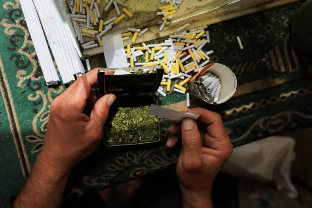 بائع فلسطيني يبيع سجائر مصنوعة من أوراق الملوخية المجففة كبديل للتبغ (رويترز)