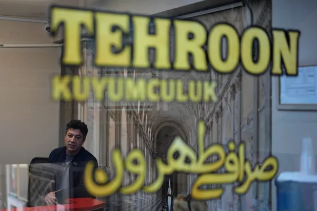 Iranian Serdar Taghizade speaks to a customer inside his currency exchange business in Istanbul on Monday, April 13, 2026. (AP Photo/Khalil Hamra)