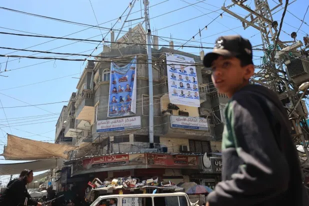 Election campaign banners showing candidates for the upcoming municipal elections hang on a building in Deir al-Balah in the central Gaza Strip on April 21, 2026. (AFP)