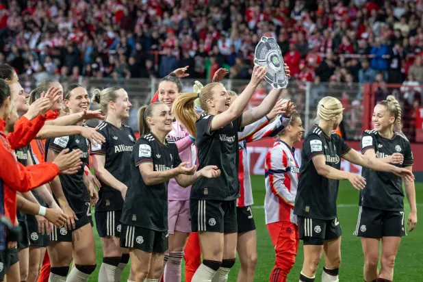 تحتفل لاعبات بايرن ميونيخ بالفوز وهن يحملن نسخة من درع البطولة عقب صافرة النهاية (د.ب.أ)