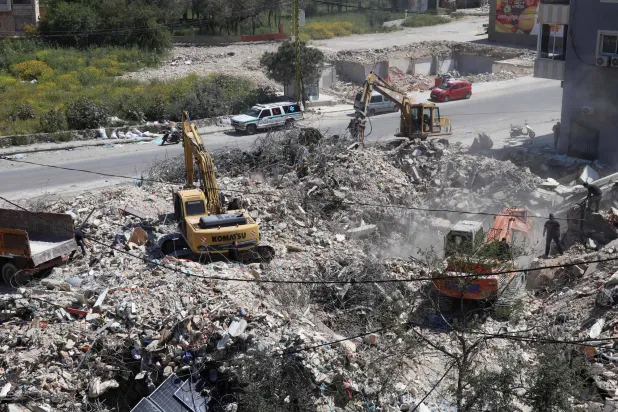 
فرق الإنقاذ تزيل الأنقاض أمس من مبنى قصفه الجيش الإسرائيلي في بلدة حناويه بجنوب لبنان (أ.ف.ب)