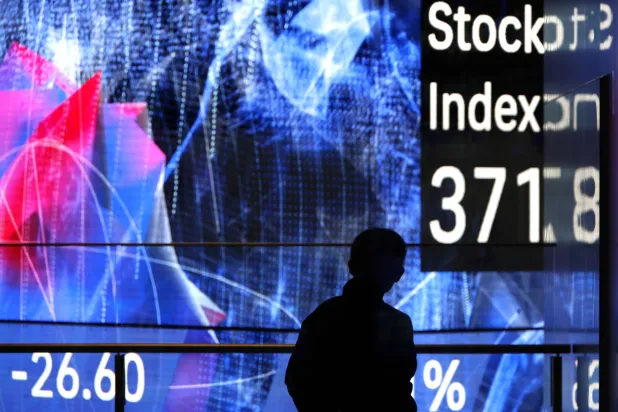 رجل يقف أمام لوحة مؤشرات سوق الأسهم في طوكيو (إ.ب.أ)