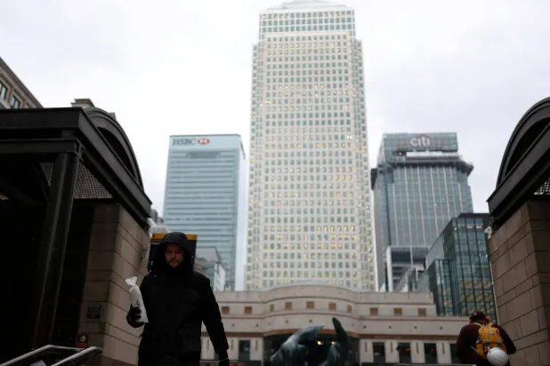 عمال يسيرون عبر ساحة كابوت في منطقة كاناري وارف المالية (لندن)