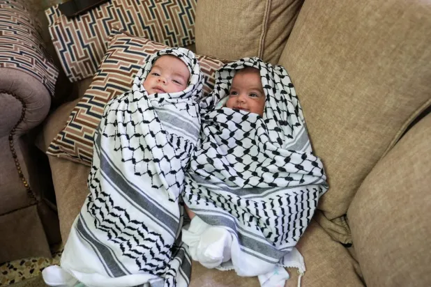 ابنتا الشاب الفلسطيني عودة عواودة (25 عاماً) الذي قُتل في هجوم استيطاني إسرائيلي خلال جنازته قرب رام الله في الضفة الغربية الخميس (رويترز)