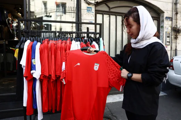 إيرانية تعاين قميص منتخب بلادها بأحد متاجر طهران (رويترز)