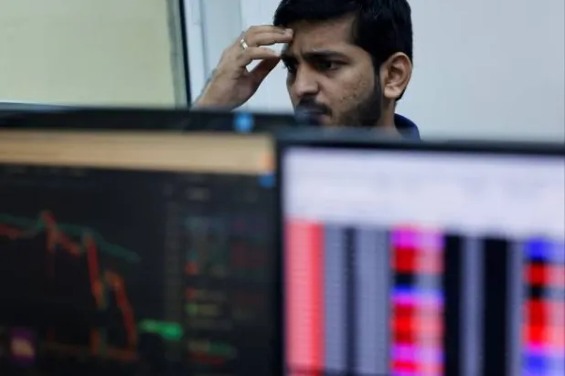 متداول أسهم أثناء مزاولته عمله داخل شركة وساطة مالية في مومباي (رويترز)