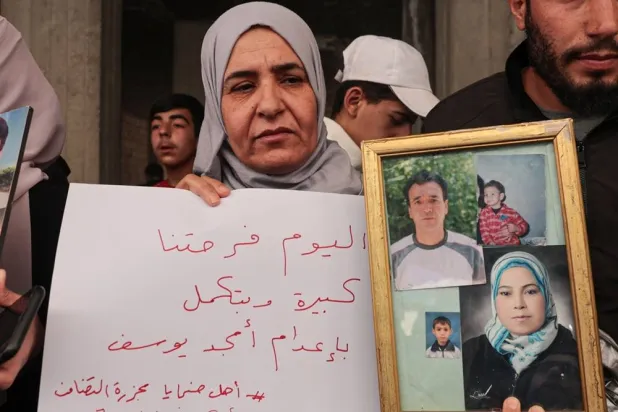 A woman holds photos of her relatives who were killed in the Tadamon massacre during a celebration after the arrest of Amjad Youssef, the main perpetrator in the massacre, in the Tadamon neighborhood, Damascus, Syria, 24 April 2026. (EPA) 