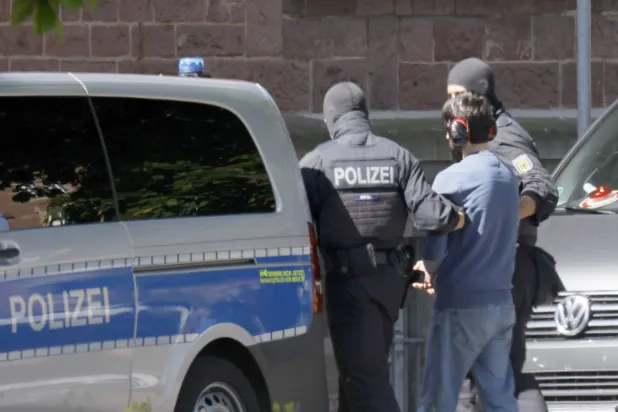 ضباط من الشرطة الفيدرالية الألمانية يرافقون مشتبَهاً به إرهابياً من مروحية إلى المحكمة الفيدرالية العليا في كارلسروه (أرشيفية-إ.ب.أ)