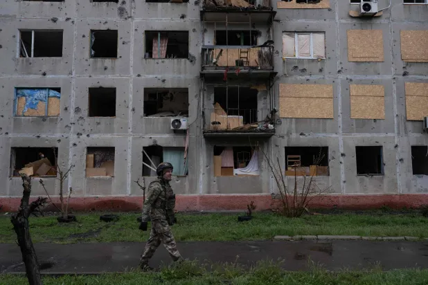 جندي أوكراني وهو يمر بجوار مبنى متضرر في ضواحي دروجكيفكا بمنطقة دونيتسك (أ.ف.ب)