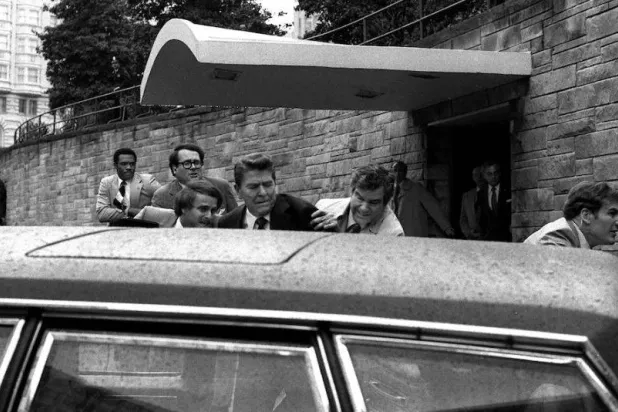 رونالد ريغان يُدفَع إلى سيارة من قبل الأمن بعد محاولة اغتياله عام 1981 (أ.ب)