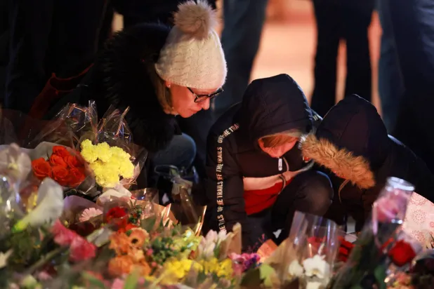 سويسريون يشعلون الشموع أمام حانة في منتجع تزلج سويسري اشتعلت بها النيران ليلة رأس السنة (رويترز)