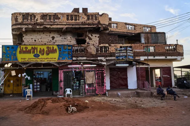 Shops operate beneath a war-damaged building in Omdurman, on the outskirts of Khartoum, Sudan, Thursday, April 23, 2026. (AP Photo/Bernat Armangue)