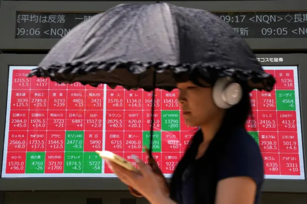 (foto altı) Tokyo Borsası’nda Nikkei endeksinin hisse senedi fiyatlarını gösteren elektronik panonun önünden geçen bir kadın (AFP)