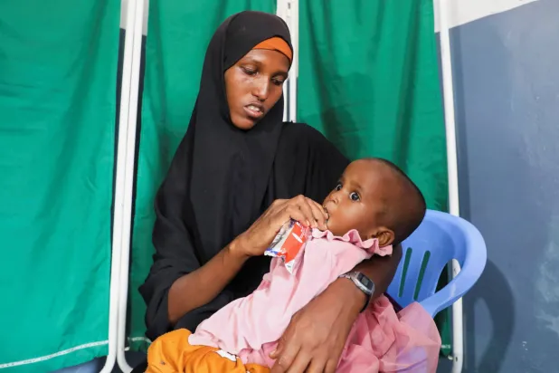 Fatima Mohamed feed Iqlas Omar Abdi, 1, with nutritious supplementary biscuit at the Daynile hospital as shortages of lifesaving therapeutic foods caused by shipping disruptions due to the Iran war have forced clinics treating severely malnourished children to turn away patients and ration supplies in drought-hit Somalia, in Daynile district of Mogadishu, Somalia April 20, 2026. (Reuters)