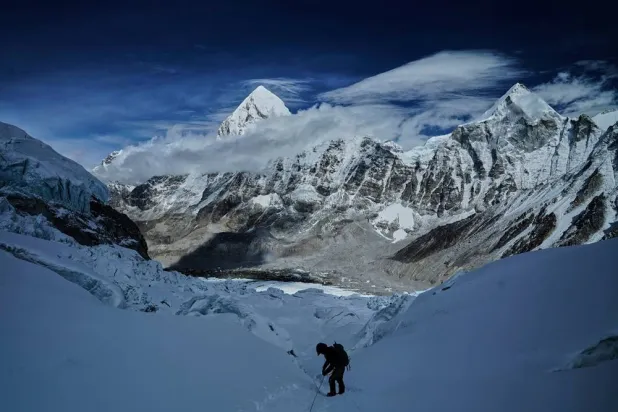 Mount Pumori, center left, looms in the background as a mountaineer negotiates Khumbu Icefall to descend to Everest Base Camp, in Nepal, May 4, 2025. (AP)