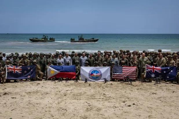 Troops from New Zealand, the Philippines, US, and Australia pose for a photo with their national flags after participating in counter-landing live fire exercises during Balikatan, the annual joint military exercises between the US and the Philippines, at Long Point Beach, Brgy. Aporawan, Aborlan, Palawan, Philippines, April 27, 2026. (Reuters) 