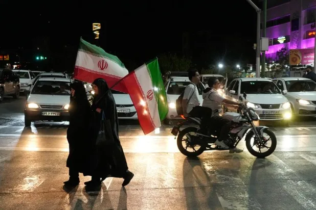  Women carry Iranian flags as they cross an intersection to attend a pro-government gathering in Tehran, Iran, Monday, April 27, 2026. (AP) 