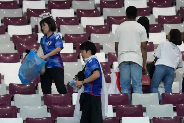 Japan supporters clean the stands at the end of the World Cup group E football match between Germany and Japan, at the Khalifa International Stadium in Doha, Qatar, Wednesday, Nov. 23, 2022. (AP)