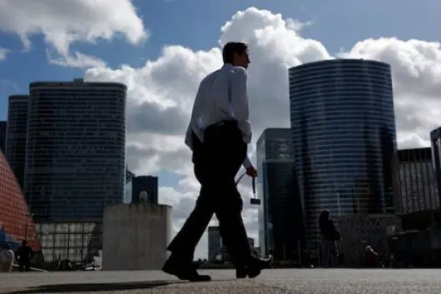 شخص يسير بجوار ناطحات السحاب في الحي المالي والتجاري في بوتو بالقرب من باريس (رويترز)