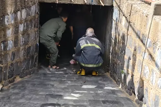 يمنيان من الدفاع المدني داخل قناة تصريف المياه يبحثان عن طفل جرفته السيول في تعز (إعلام محلي)