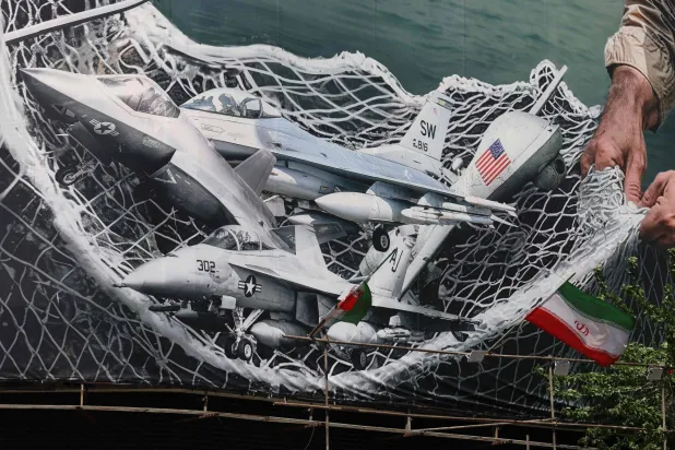  لافتة دعائية عملاقة تُظهر قوات إيرانية تستخدم شبكة لصيد طائرات مقاتلة أميركية، في ساحة انقلاب (الثورة) بطهران في 28 أبريل (أ.ف.ب)