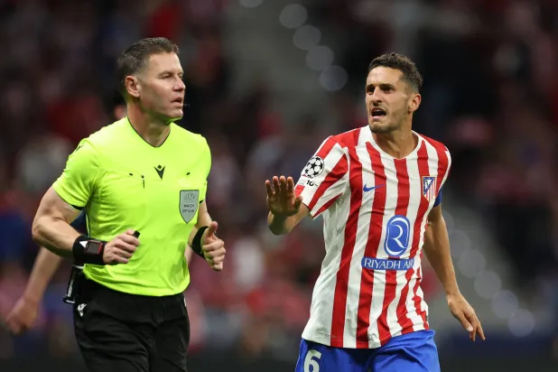 كوكي لاعب أتلتيكو مدريد يتحدث مع الحكم داني ماكيلي قبل مراجعة تقنية الفيديو لاحتمال احتساب ركلة جزاء (رويترز)