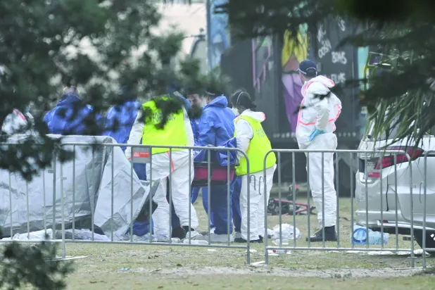 خبراء الأدلة الجنائية خلال معاينة جثة أحد الضحايا بموقع إطلاق النار بشاطئ بونداي في سيدني (أرشيفية - إ.ب.أ)