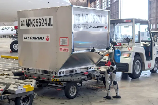 روبوت بشري الشكل يدفع حاوية خلال عرض إعلامي في مطار هانيدا بطوكيو (إ.ب.أ)