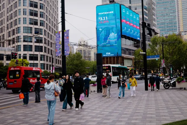 شاشة عملاقة تعرض حركة الأسهم بأحد ميادين مدينة شنغهاي الصينية (إ.ب.أ)