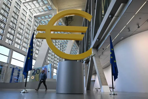 رجل يمر بجانب شعار اليورو بمركز الزوار التابع للبنك المركزي الأوروبي في فرنكفورت (أ.ف.ب)